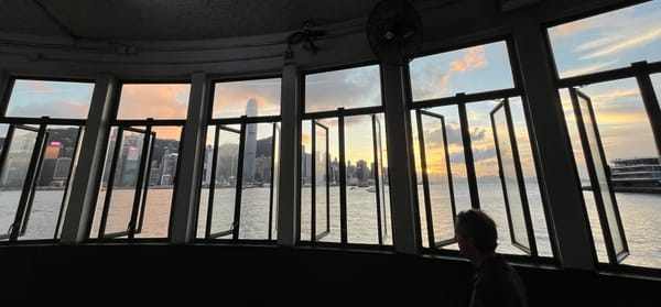 Panorama of sun setting behind the Hong Kong Island skyline, viewed through the windows of the TST Star Ferry Pier.